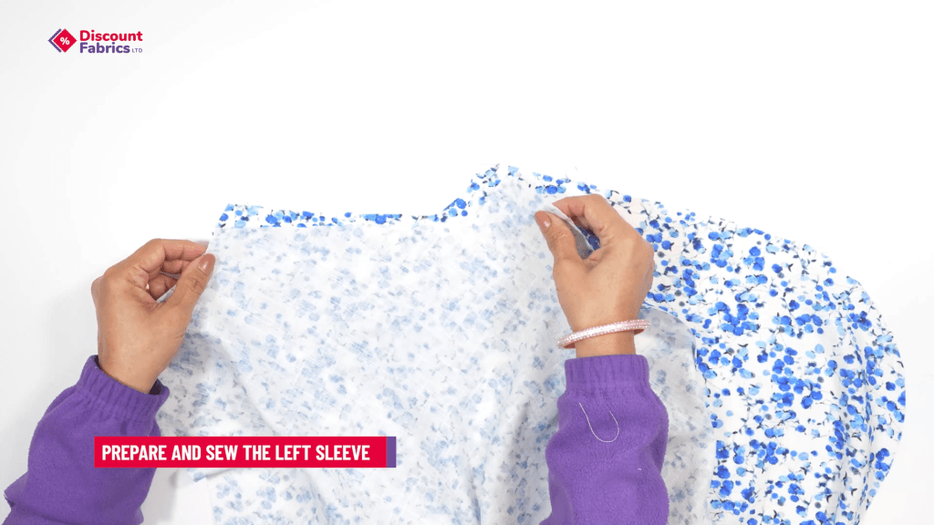 Two hands holding blue and white floral fabric, positioned against a white background. A purple sweater is visible, and a text overlay reads,