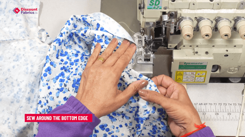 A person is sewing a floral blue and white fabric with an overlock machine. The person's hands adjust the fabric. Text on the image instructs to