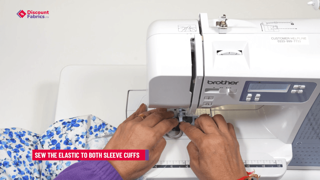 A person is using a sewing machine to attach elastic to a garment. Their hands are guiding the fabric, which has a blue and white floral pattern. A text box reads,